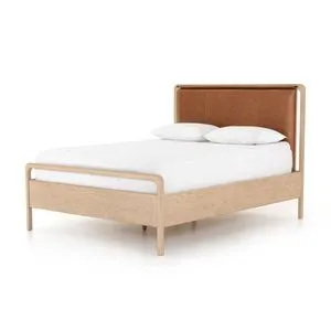 Angled front view of bed with white bedding highlighting leather headboard and oak frame
